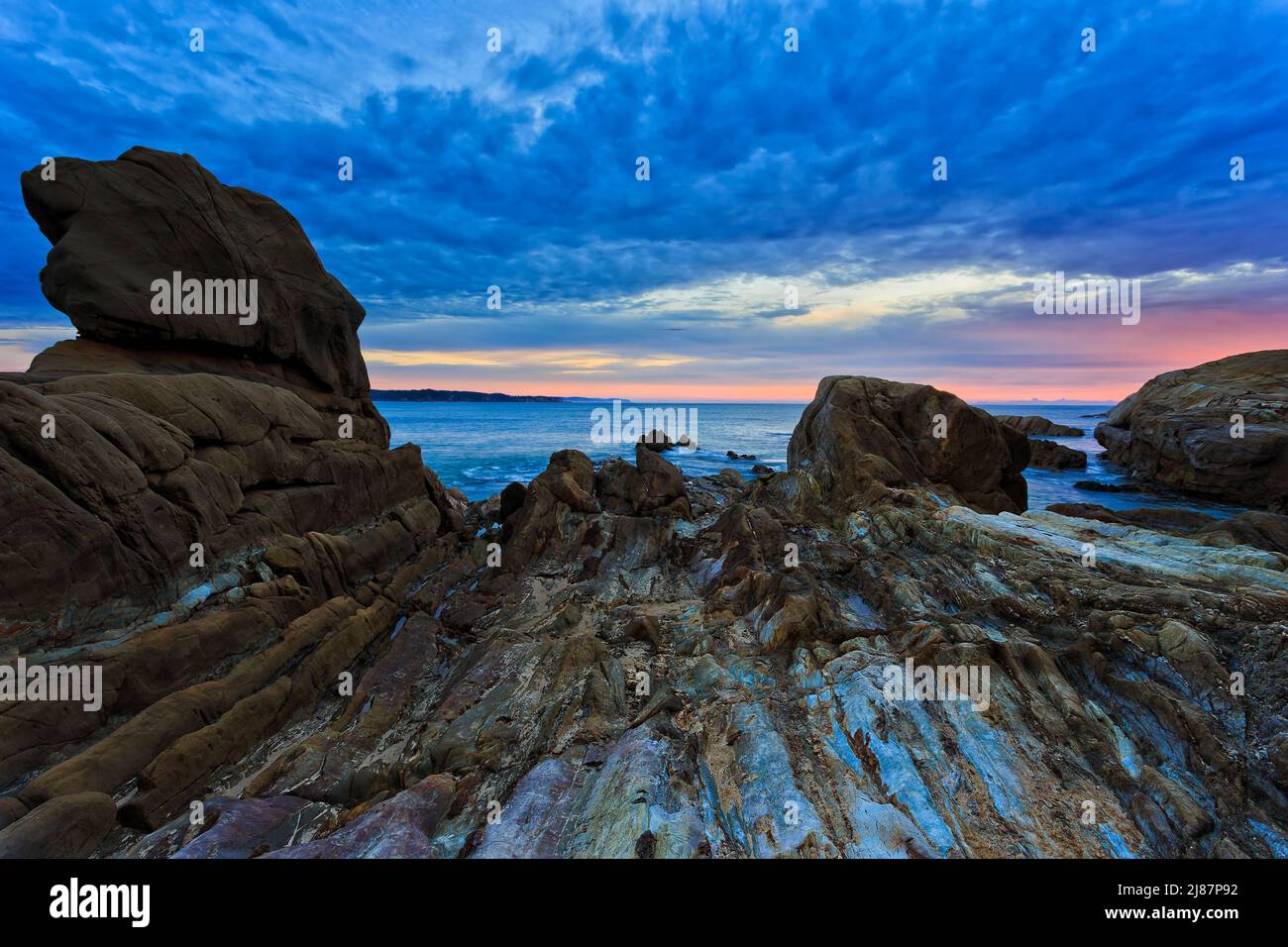 Meerwasser erodierte Felsen am Strand von Tathra an der Sapphire Coast in Australien - Sonnenaufgangslandschaft. Stockfoto