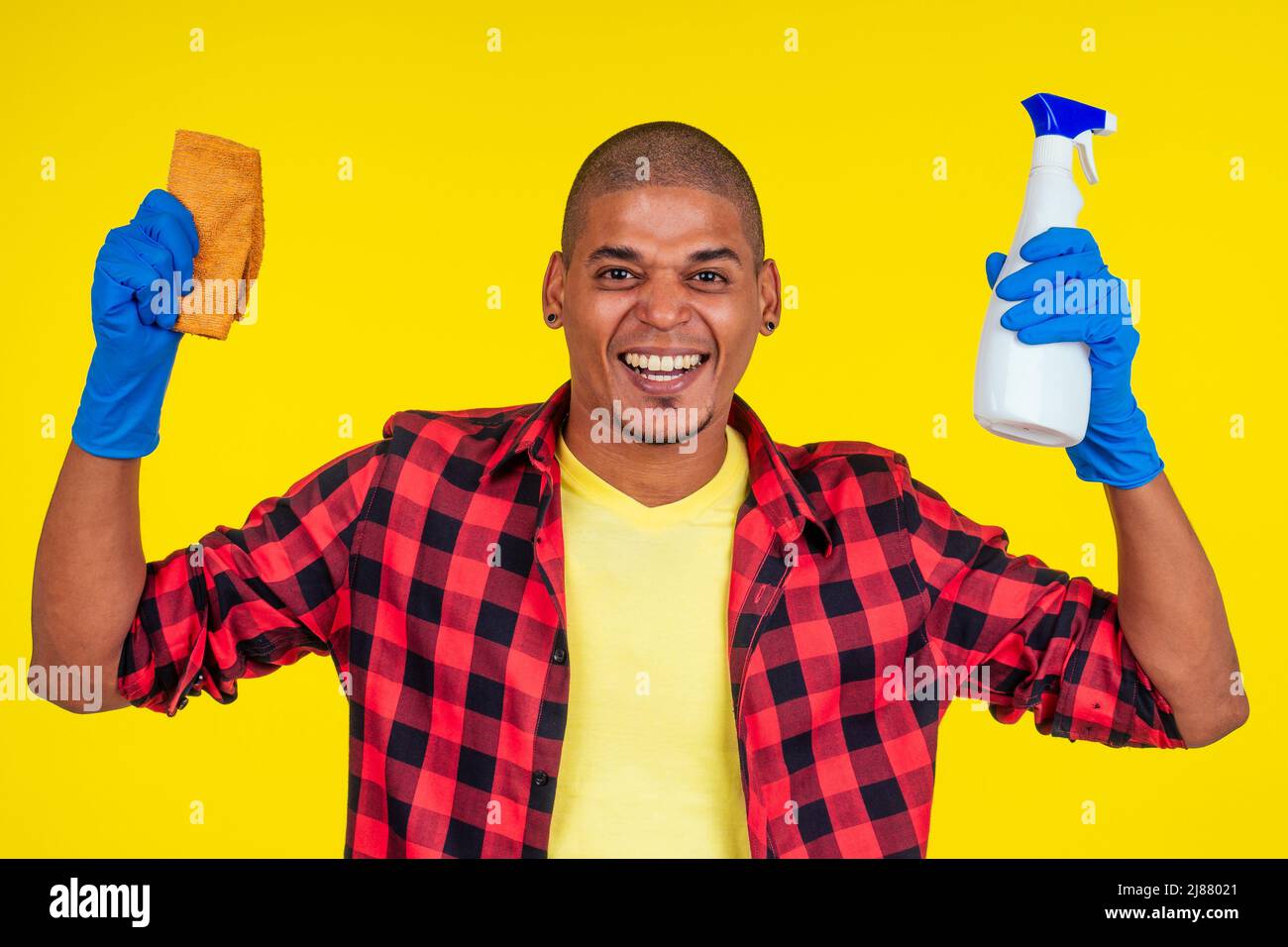 lateinamerikanischer brasilianischer Reinigungsmann mit Ribon-Handschuhen auf gelbem Hintergrund Stockfoto