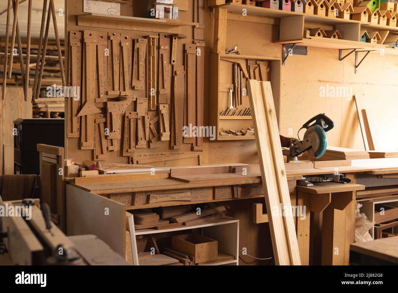 Innenraum der Werkstatt mit Brettern und verschiedenen Holzbearbeitungswerkzeugen, die in der Werkstatt auf einem Regal hängen Stockfoto