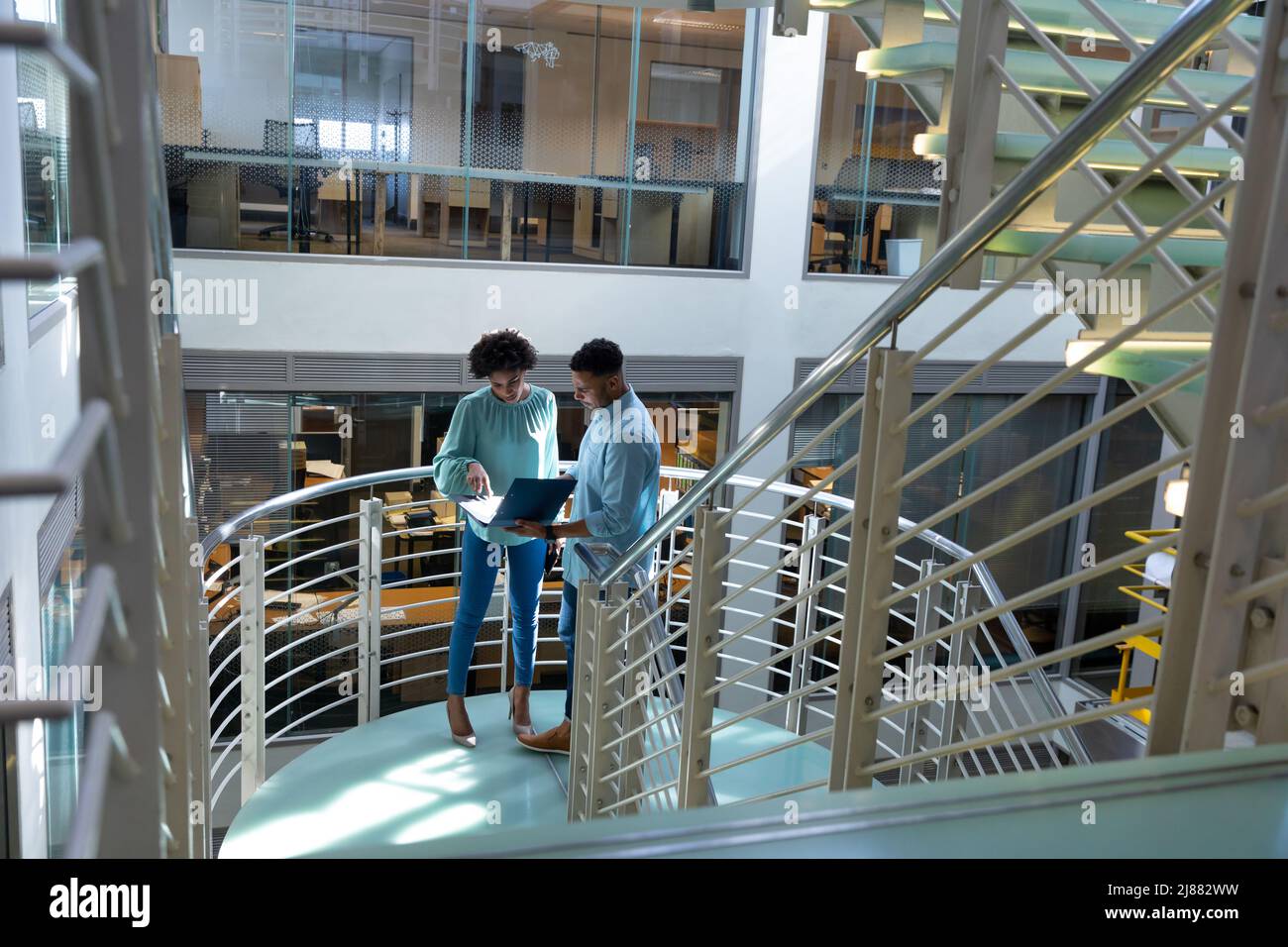 Blick aus der Perspektive afroamerikanischer Fachleute, die am Treppenhaus am Arbeitsplatz über die Akte diskutieren Stockfoto