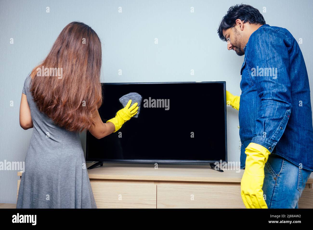 Junges Paar inder Umzug in neue Heimat, Reinigung und Auspacken große Fenster mit stilvollen gelben Curtainbackground Stockfoto