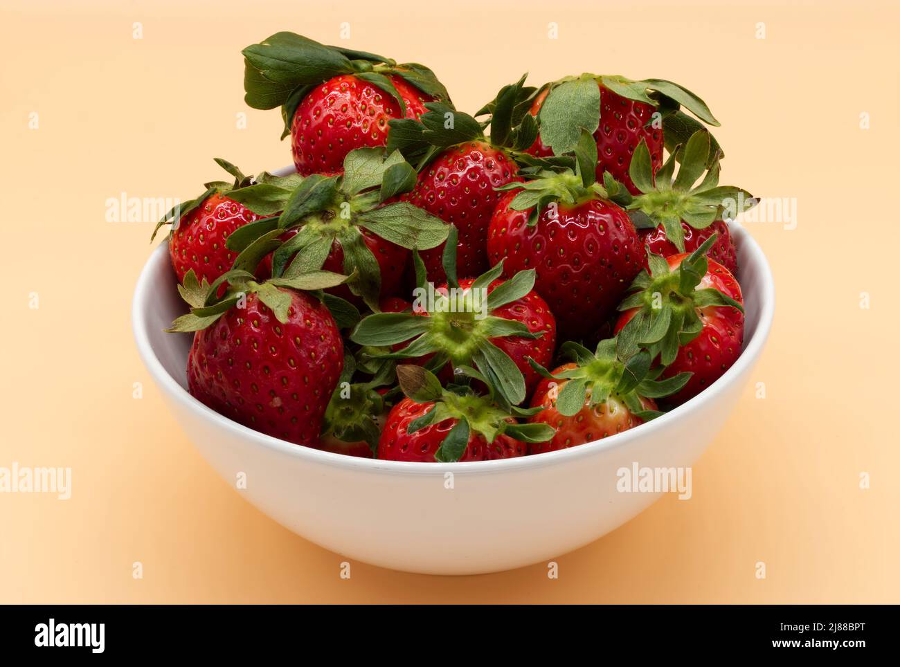 Frische Erdbeere in einer Schale isoliert auf hellorangefarbenem Hintergrund. Stockfoto