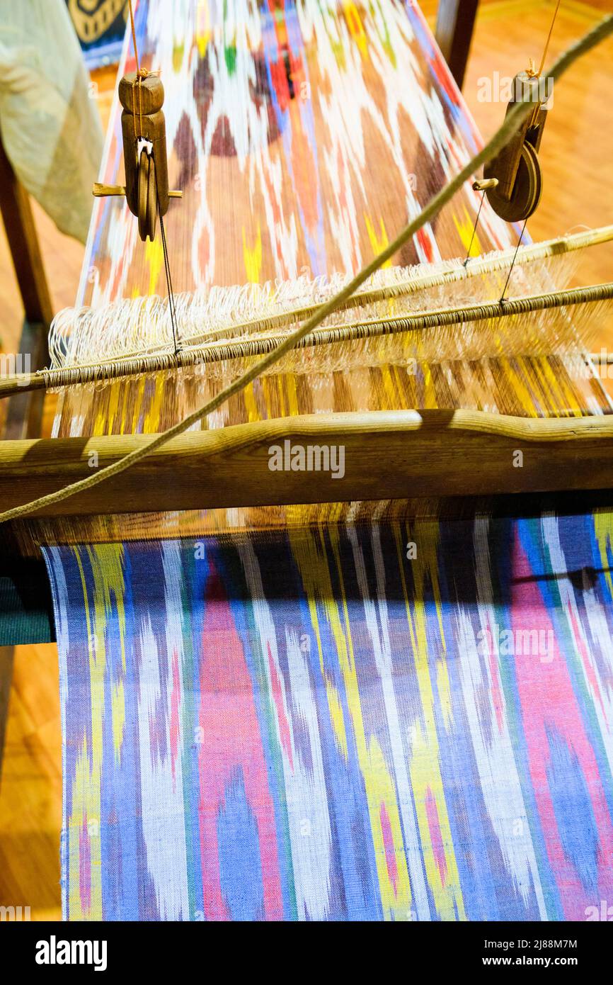 Detail des IKAT-Stoffes, der auf einem traditionellen Webstuhl gewebt wird. Im Museum für angewandte Kunst in Taschkent, Usbekistan. Stockfoto