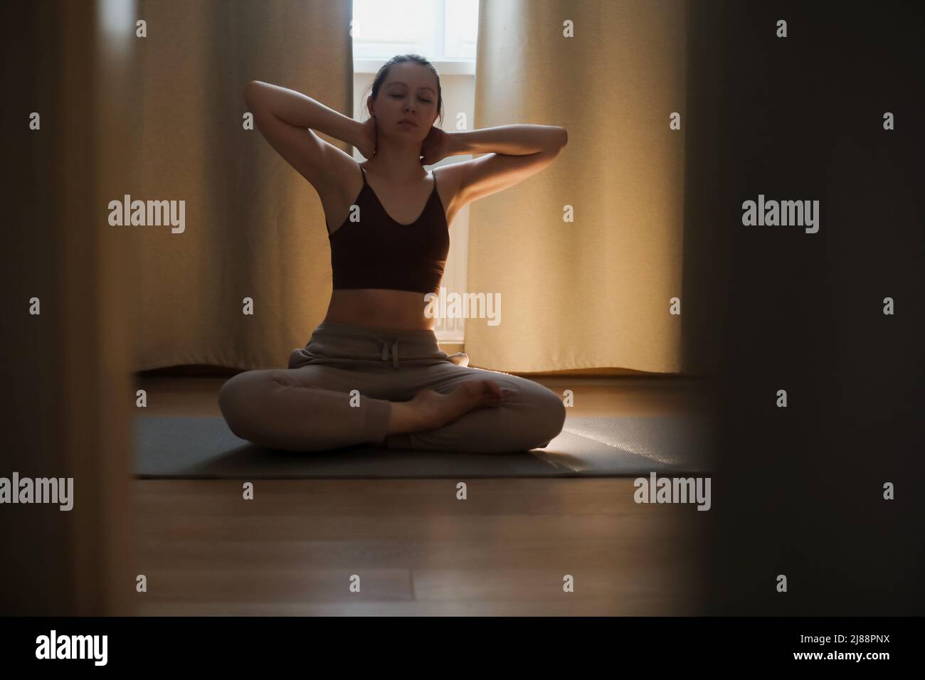 Junge Frau macht Yoga und praktiziert Meditation zu Hause. Meditation und psychische Gesundheit Konzept Stockfoto