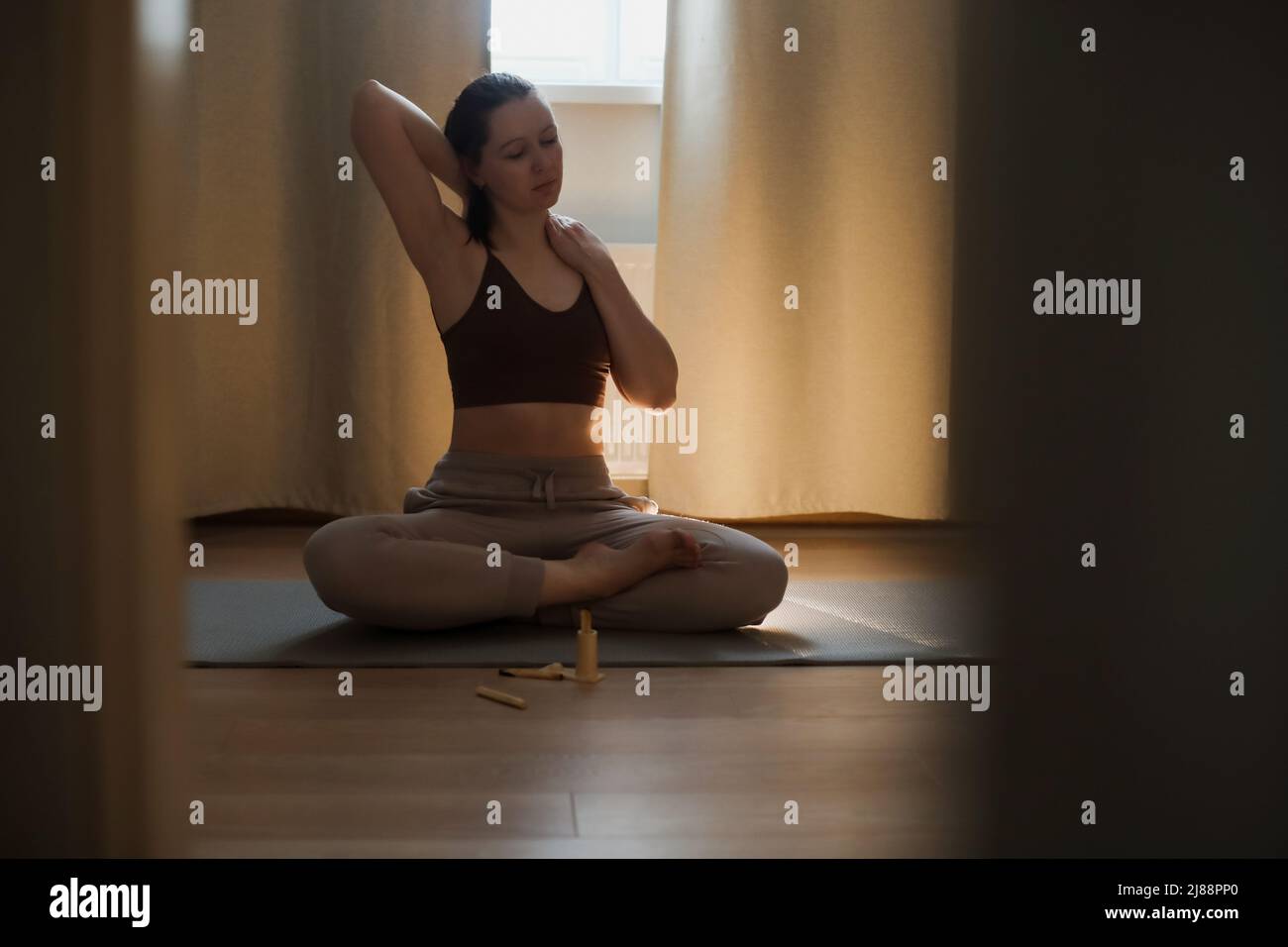 Junge Frau macht Yoga und praktiziert Meditation zu Hause. Meditation und psychische Gesundheit Konzept Stockfoto