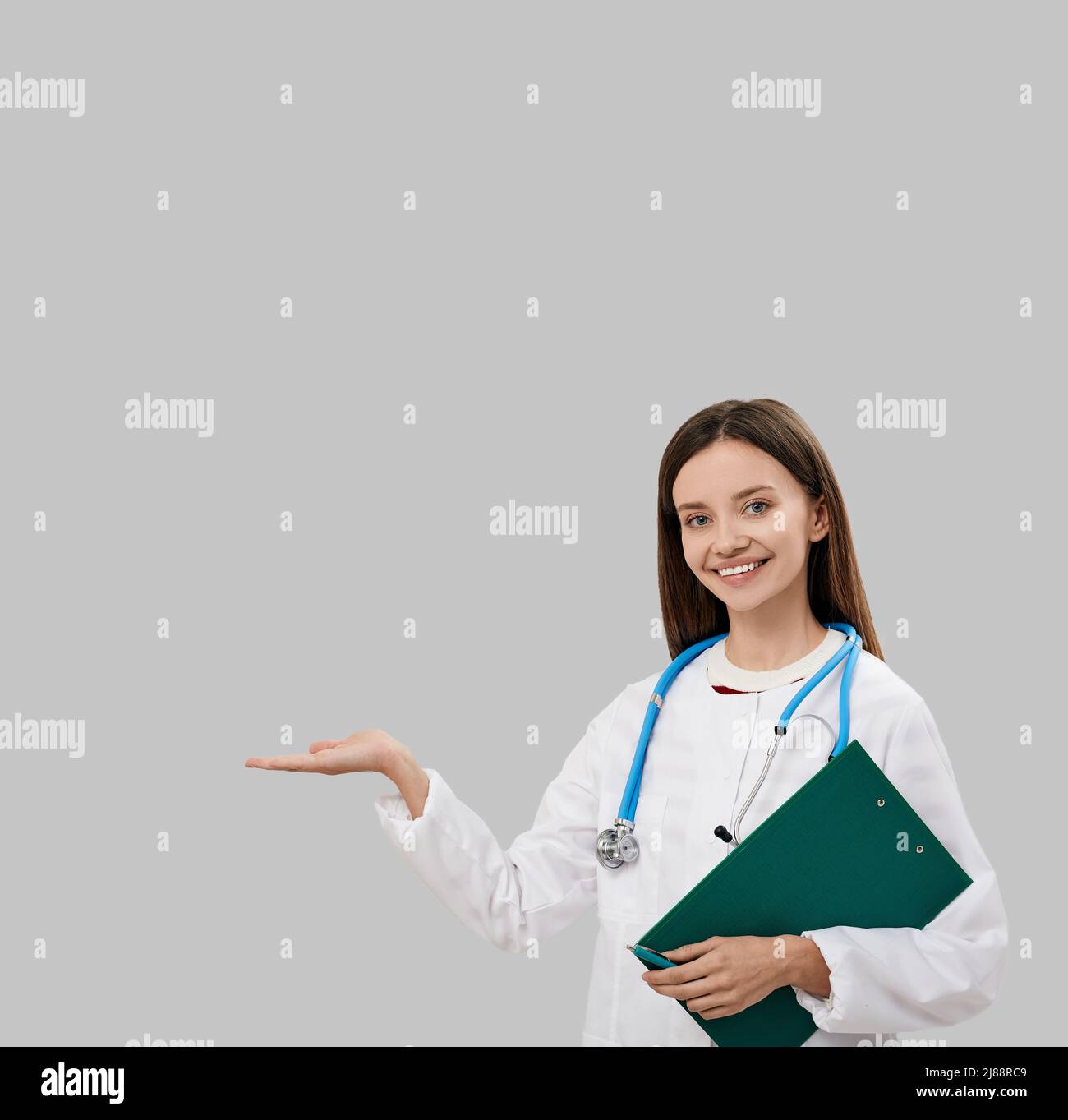 Brünette Hausärztin mit Patientenakte stehend und auf leeren Platz für Ihren Anzeigetext. Medizinische Werbung Stockfoto