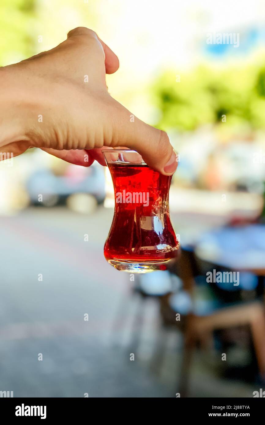 Türkischer Tee in der Hand auf dem Hintergrund der Stadt Stockfoto