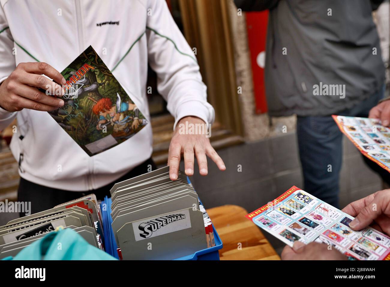 Berlin, Deutschland. 14.. Mai 2022. Vor dem Comic-Laden „Grober Unfug“ im Berliner Bezirk Kreuzberg nimmt ein Mitarbeiter Comic-Bücher für potenzielle Kunden heraus. Am „Free Comic Book Day“ verschenken Geschäfte Comics. Einmal im Jahr können Sie einen Comic-Buchladen besuchen und vor Ort ein paar Comic-Bücher kostenlos erhalten. Die Idee kam aus den USA. Quelle: Carsten Koall/dpa/Alamy Live News Stockfoto