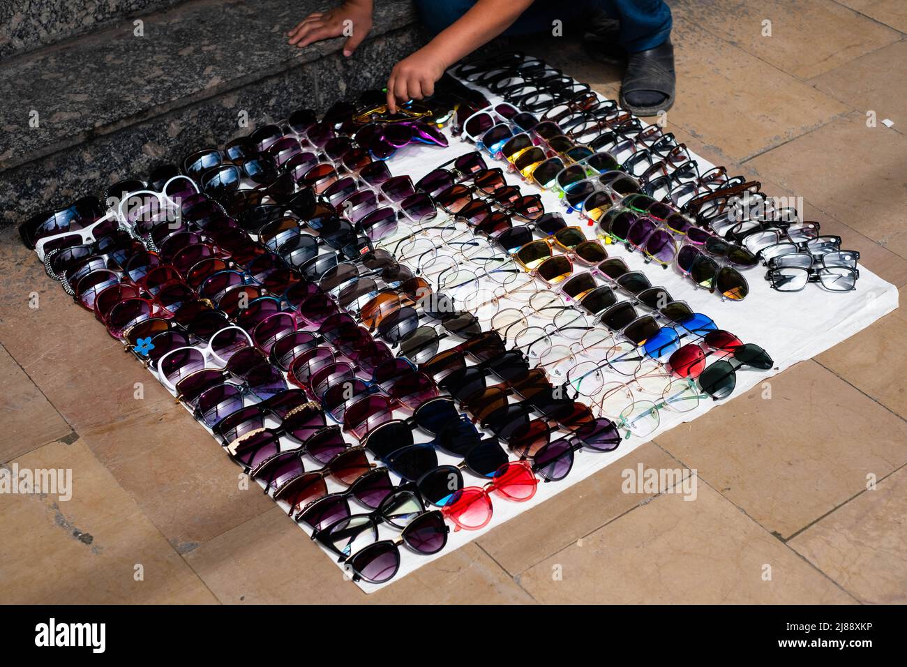 Kind verkauft Sonnenbrillen auf der Straße Stockfoto