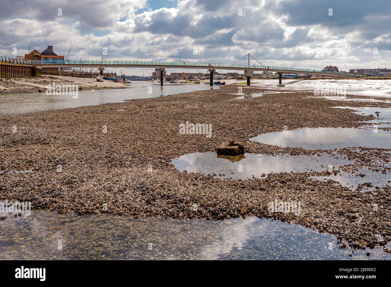 Der Fluss Adur bei Ebbe, mit Blick auf die Fußgängerbrücke und enthüllt ein ausgedehntes Flussbett und einen alten Ankerplatz - Shoreham-by-Sea, Sussex. Stockfoto