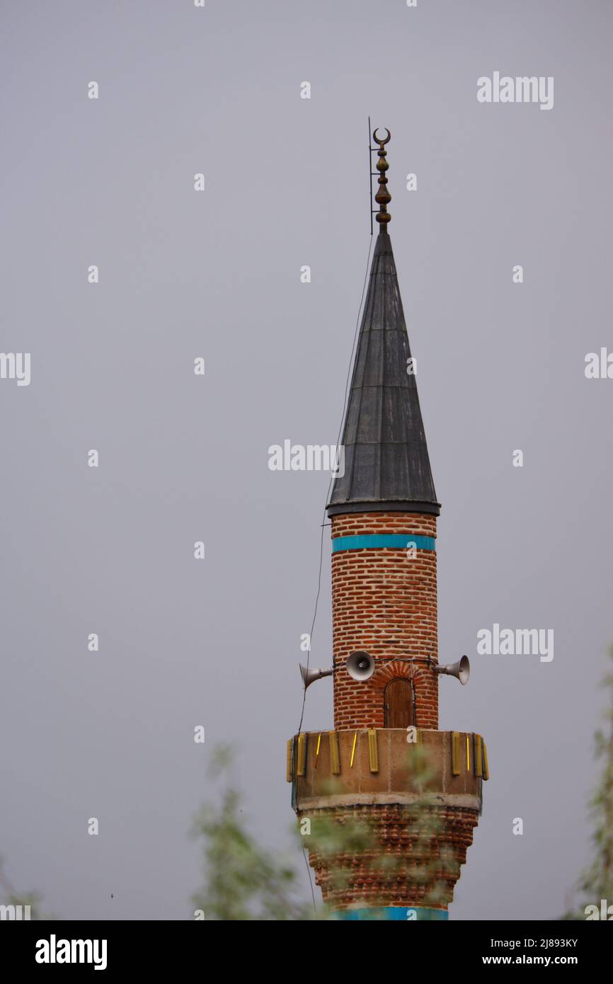 Historisches Steinminarett im osmanischen Stil bei dunklem, bewölktem Wetter Stockfoto