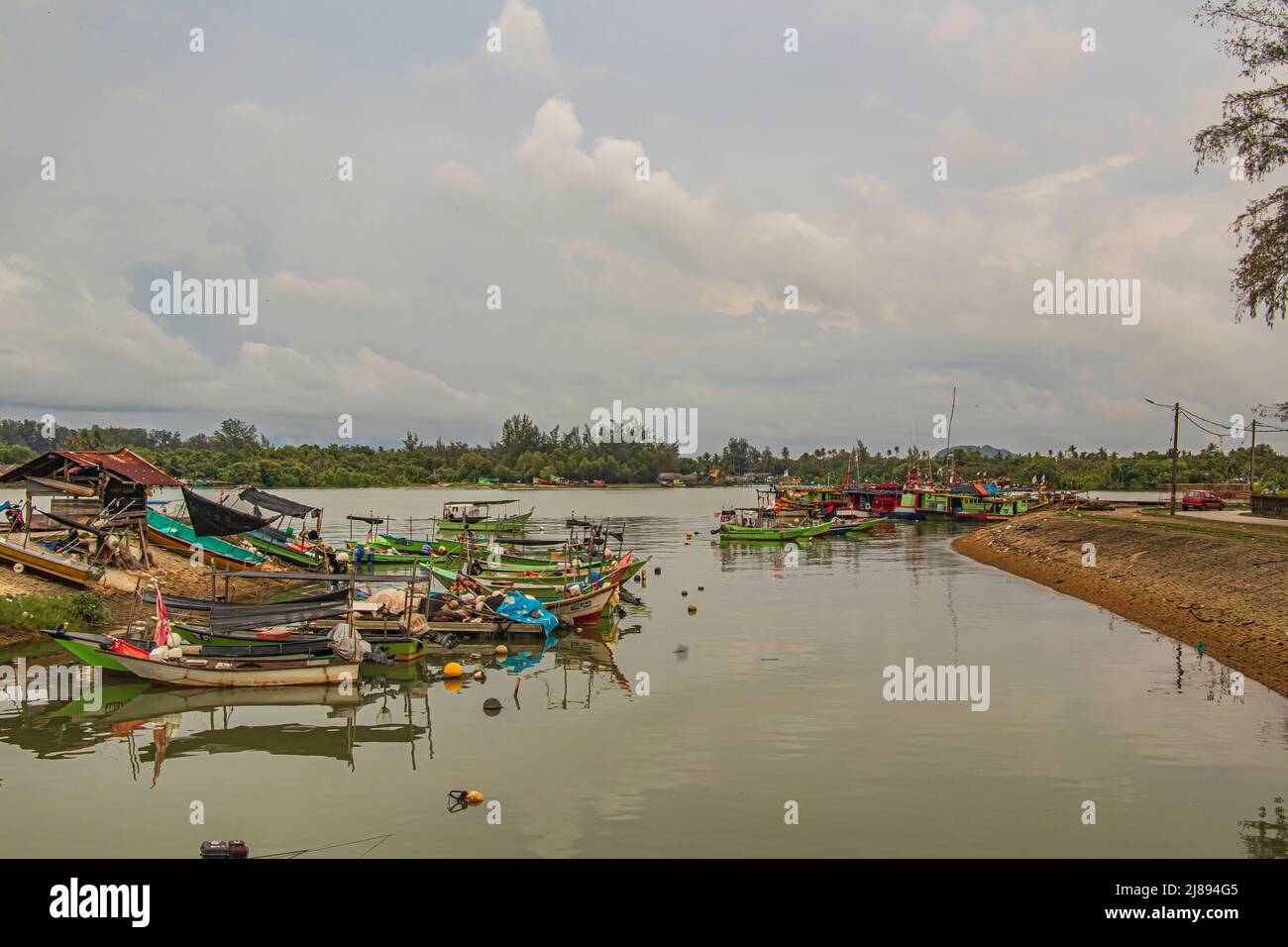 Fischerboot, das bei bewölktem Wetter des eintreffenden Regensturms an der Mündung des Sungai Besut River in Terengganu, Malaysia festmacht. Stockfoto