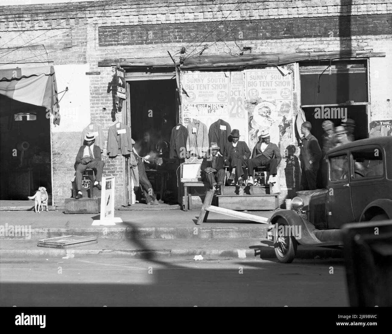 Gehsteig-Szene in Selma, Alabama. [Afroamerikaner vor einem Geschäft, in dem Second-Hand-Kleidung verkauft wird; werben für „J.C. Lincoln's Sunny South Big Tent Show“, eine Minstrel-Show]. Stockfoto