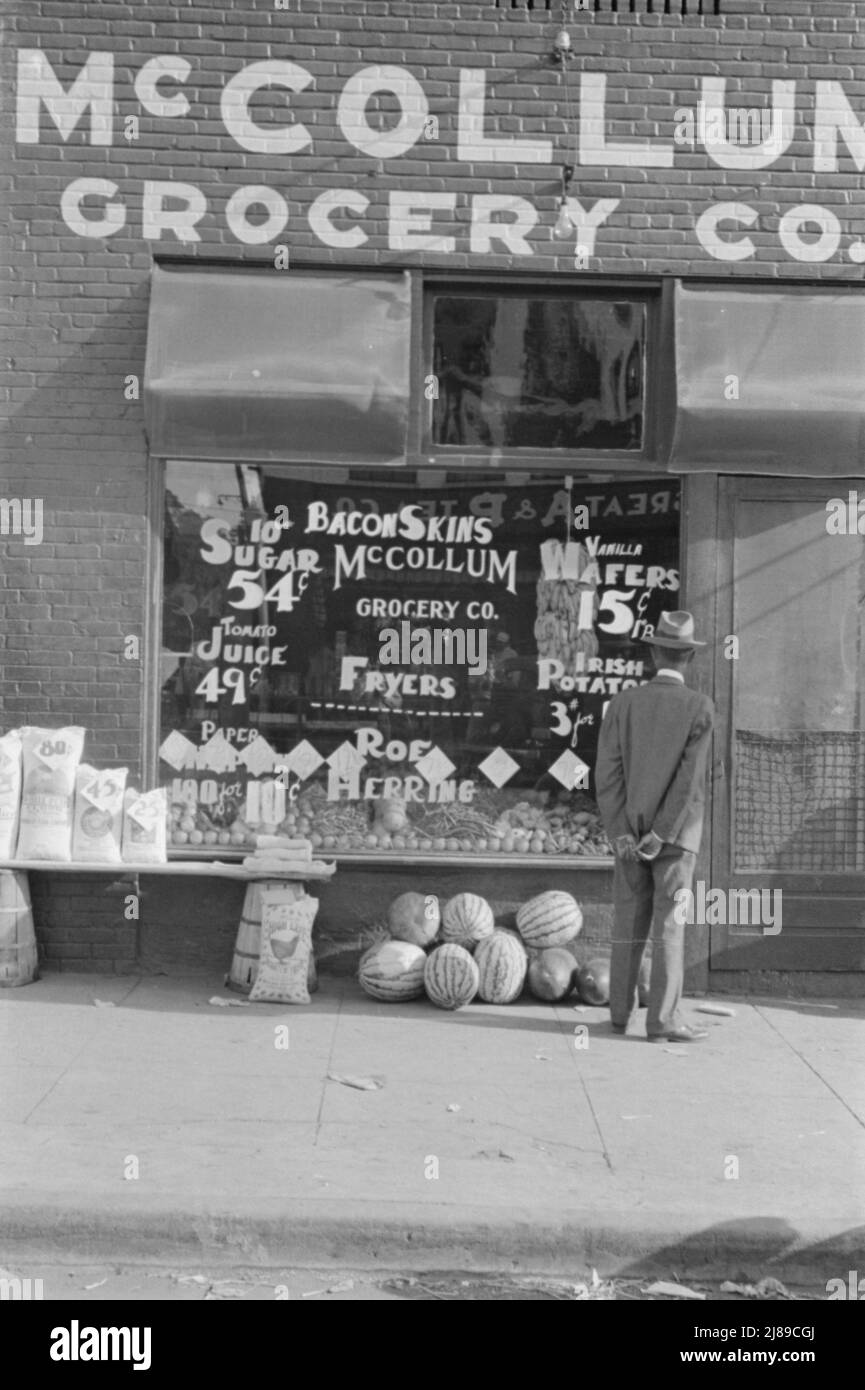Storefront, Greensboro, Alabama. ['McCollum Grocery Co.; Zucker, Tomatensaft; Papierservietten; Speck-Felle; Foyers, Roe Hering, Vanilla Wafer, Irish Potatoes“. Gezeigt werden: Säcke mit Mehl und Hühnerfutter, Wassermelonen, Bohnen, Bananen]. Stockfoto