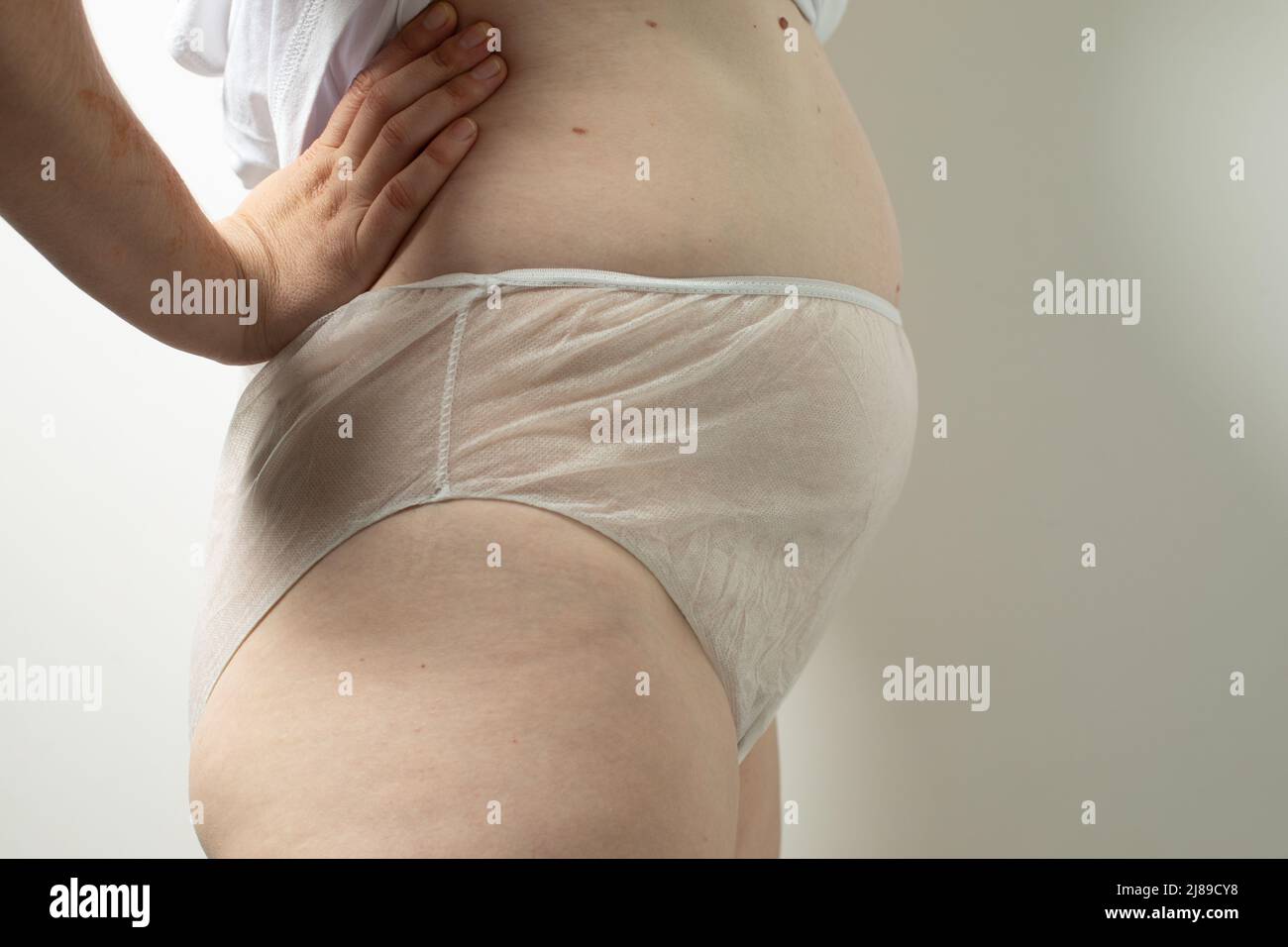 Weiblicher postpartaler Bauch in Einweg-Unterhosen, Konzept der postpartalen Erholung Stockfoto