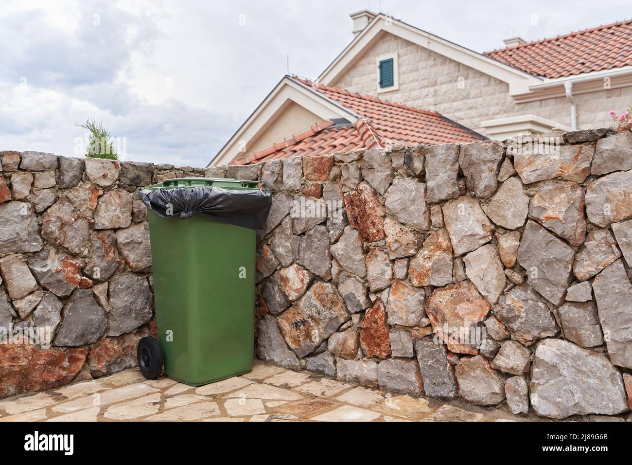 Grüner Abfalleimer neben dem Haus auf dem Hinterhof Stockfoto