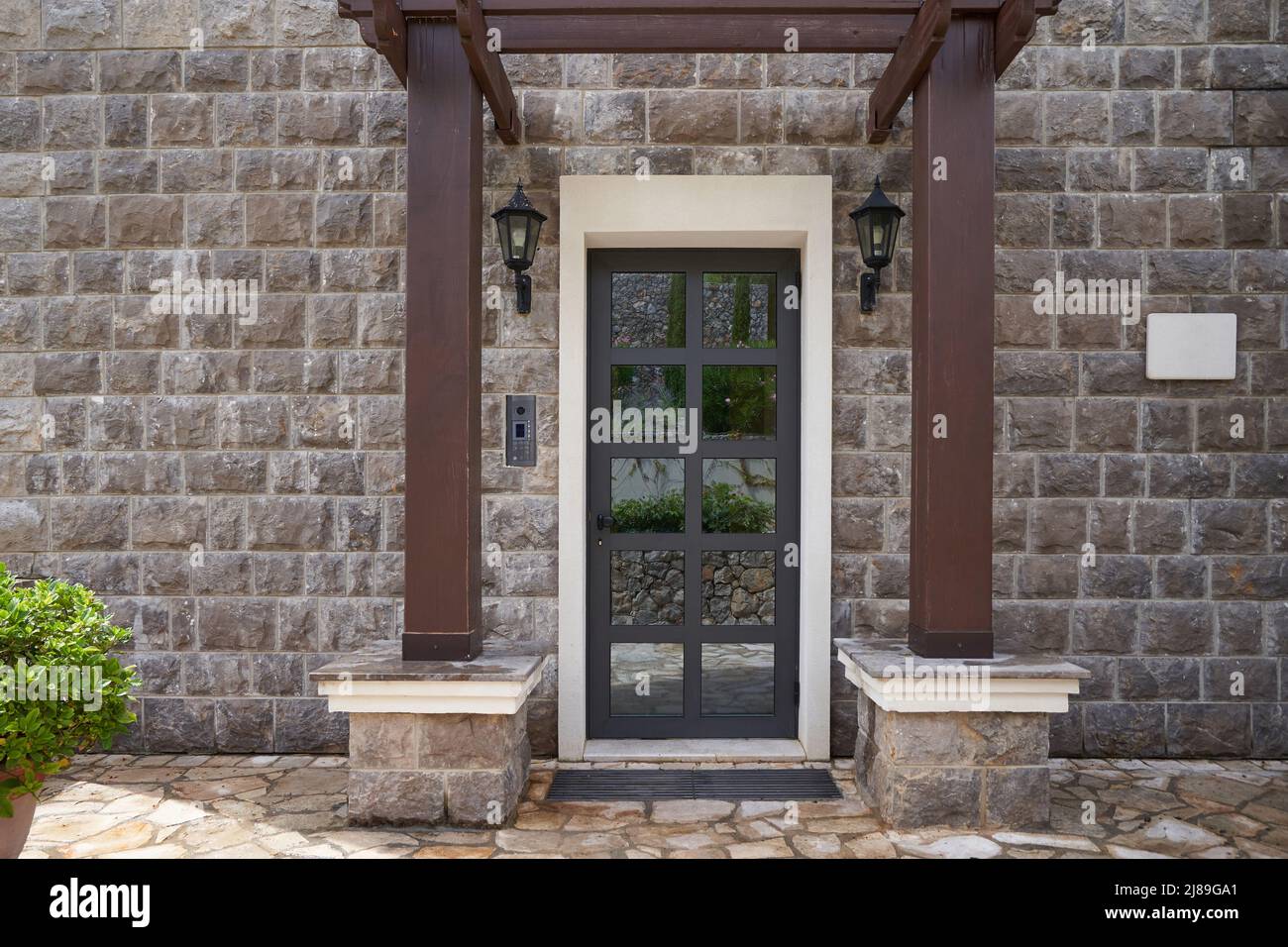 Eingang zum Haus mit Glastür und Steinmauer Stockfoto