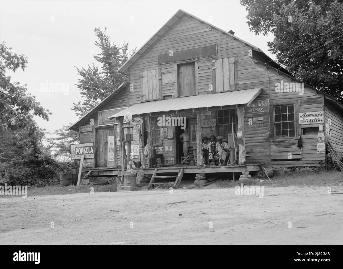 Country Store auf Feldweg, Sonntagnachmittag. Beachten Sie die Kerosin-Pumpe rechts und die Benzinpumpe links. Der Bruder des Besitzers des Ladens steht im Eingang. In Der Nähe Von Gordenton, North Carolina. Stockfoto