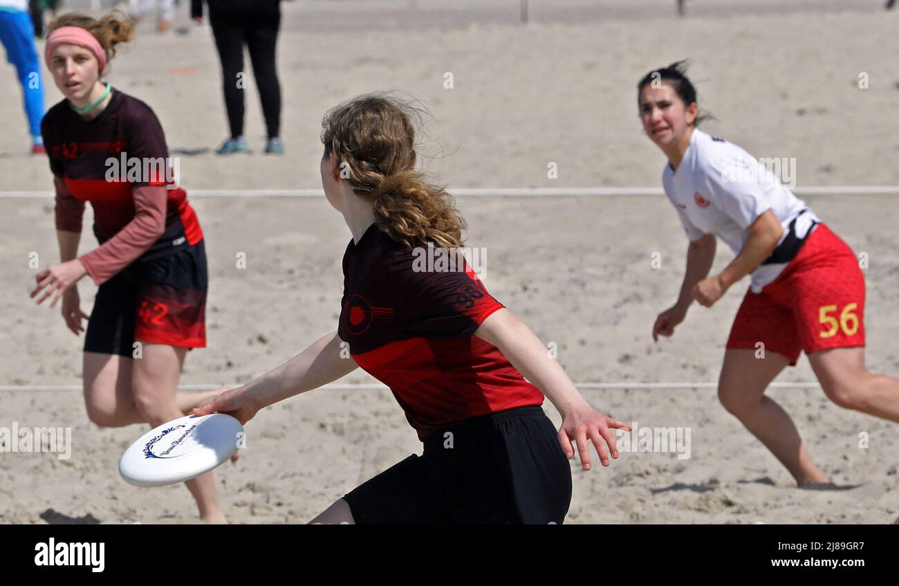 14. Mai 2022, Mecklenburg-Vorpommern, Warnemünde: Bei der Deutschen Strandfriesbeenmeisterschaft sind die Teams von Eintracht Frankfurt (weiß) und Mainzelrenner (rot) am Ostseestrand im Einsatz. Fünf Spieler pro Team versuchen, die Frisbee in die Endzone der gegnerischen Hälfte zu bringen. 21 Teams nehmen an dem zweitägigen Wettbewerb Teil. Foto: Bernd Wüstneck/dpa Stockfoto