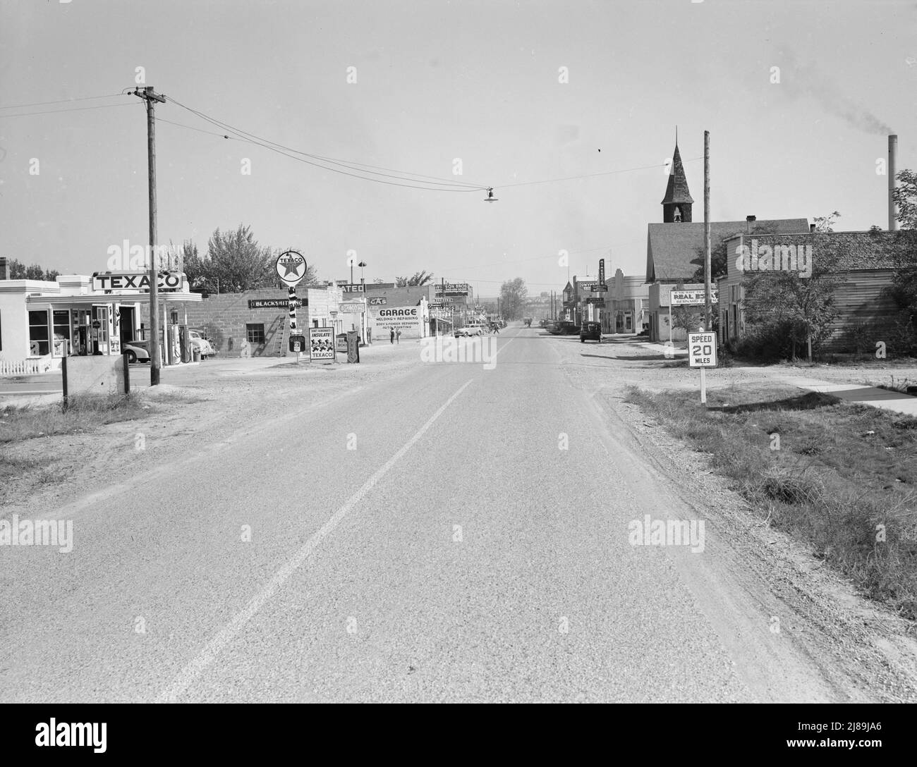 Hauptstraße von Nyssa, Oregon, am Samstagnachmittag. [Schilder: 'Texaco; nicht winterfest - isolieren!; Schmiedekunst; Café & Amp; Taverne; Gas; Garage, Schweißen &amp; Reparatur, Karosserie &amp; Fender Reparatur, Auto Painting; Wilson Bros Dry Goods; Main's Cleaners; Drugs Fountain; Atkeson's Clothing - Women's Apparel; Real Estate; Speed 20 miles']. Stockfoto