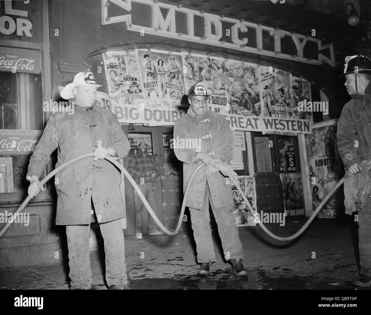 Firehouse Station Nr. 4. Washington, D.C. Reinigung eines Schlauchs vor einem Theater nach einem Brand. Der Feuerwehrmann im weißen Helm ist ein Sergeant. Stockfoto