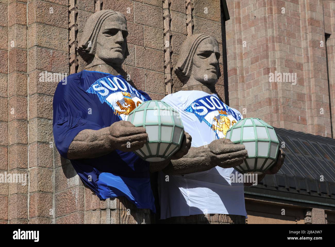 Helsinki, Finnland. 14.. Mai 2022. Die Skulpturen an der Fassade des Gebäudes des Hauptbahnhofs in Helsinki sind in T-Shirts mit Symbolen der finnischen Eishockeynationalmannschaft gekleidet. Am 13. Mai begann in Finnland die Eishockey-Weltmeisterschaft 2022. Eishockeyfans aus vielen Ländern kamen in Helsinki und Tampere an, den Städten, in denen die Spiele stattfinden werden. (Bild: © Takimoto Marina/SOPA Images via ZUMA Press Wire) Stockfoto