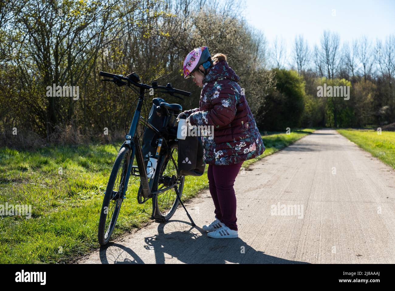 Tienen, Flemis Brabant, Belgien - 04 02 2022 - 39 Jahre altes weißes Mädchen mit Down-Syndrom, das draußen auf einem Trekkingrad steht Stockfoto