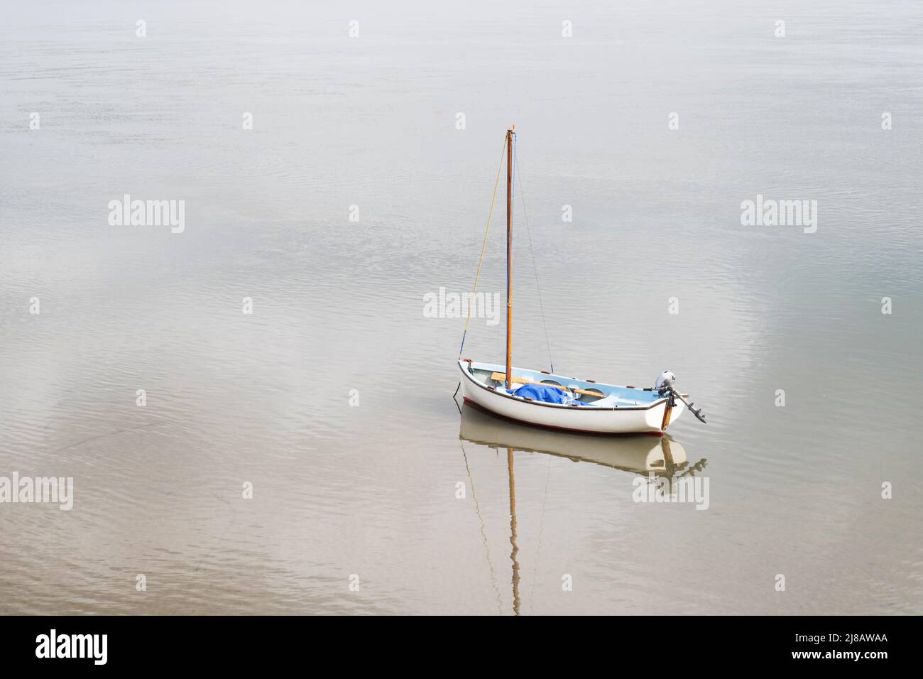 Kleines Segelboot auf ruhigem Wasser mit Reflexen. Stockfoto