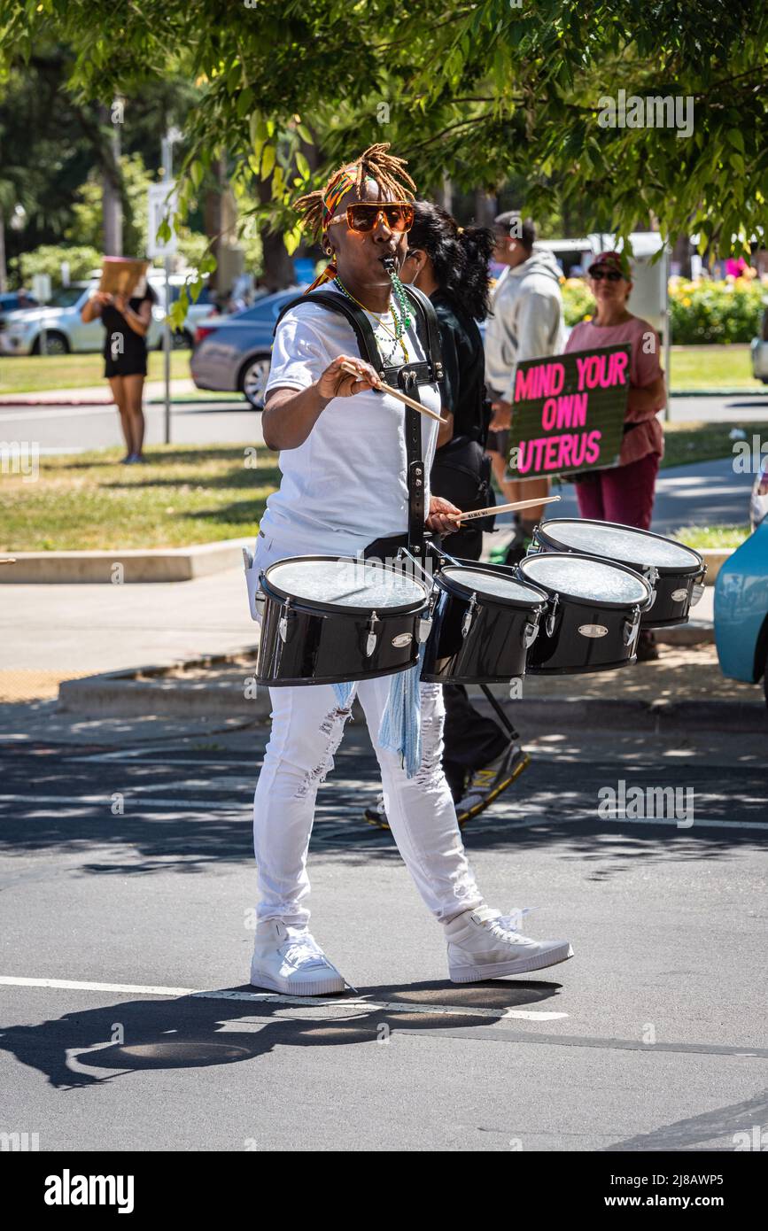 Foto eines Schlagzeugers mit Protestschild im Hintergrund, das die Roe-Verbote unserer Körper anführt Marsch und Rally organisiert von Planned Parenthood. Stockfoto