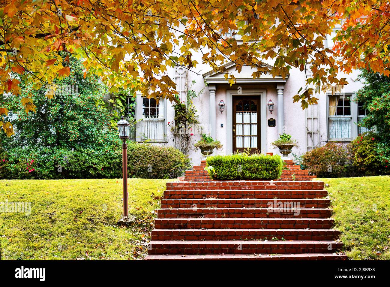 Curb Appeal - charmantes Haus mit roten Ziegeltreppen und Herbstlaub Stockfoto