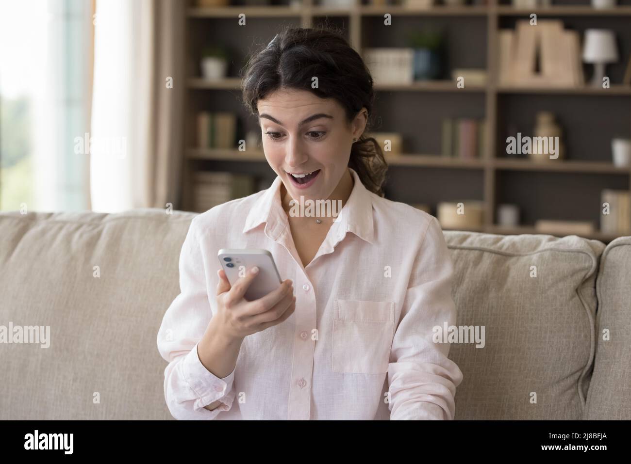 Frau, die auf den Handybildschirm starrt, fühlt sich überrascht Stockfoto