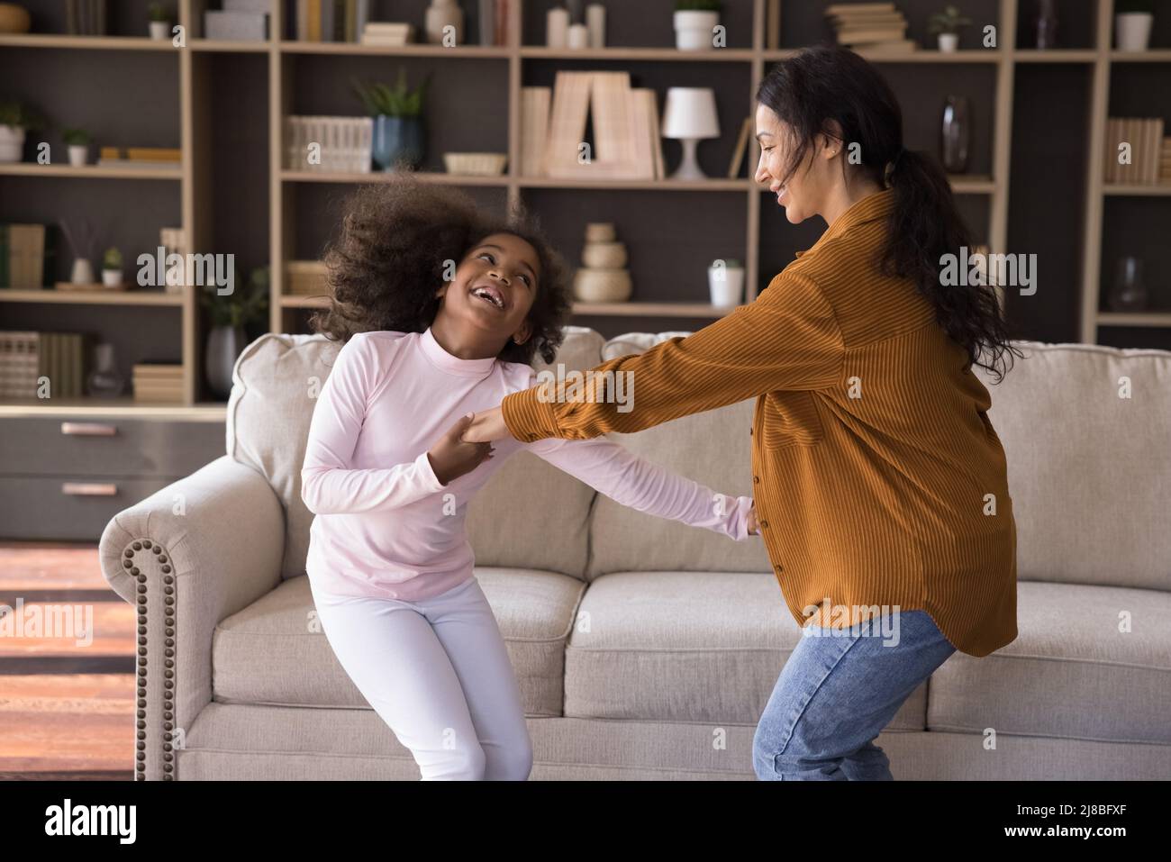 Niedliches kleines Mädchen und Mutter halten die Hände tanzend zu Hause Stockfoto