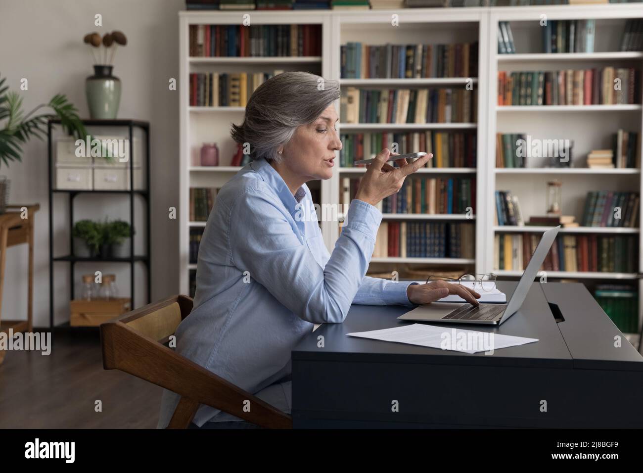 Fokussierte Geschäftsfrau, die eine Audionachricht auf dem Mobiltelefon aufzeichnet Stockfoto