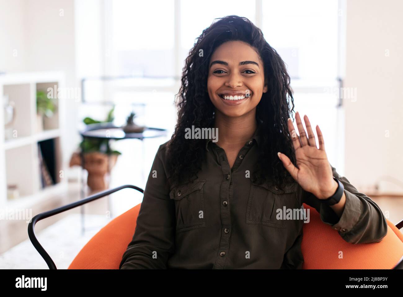 Grußkonzept. Lächelnde schwarze Frau winkt Hand an die Kamera Stockfoto