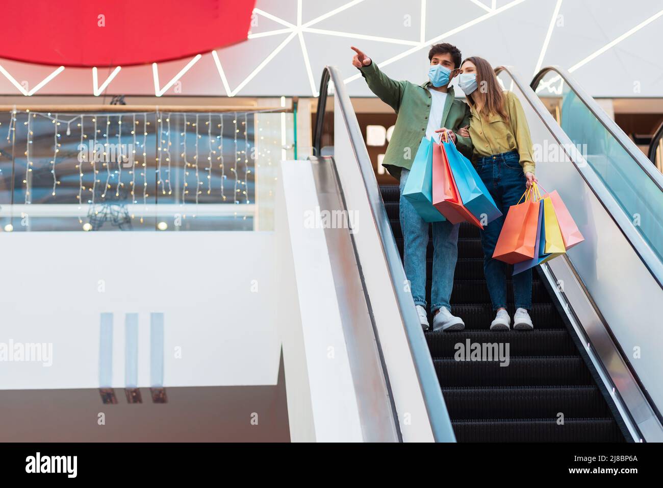 Paar Shopping In Masken Stehend Auf Beweglichen Treppen In Der Mall Stockfoto