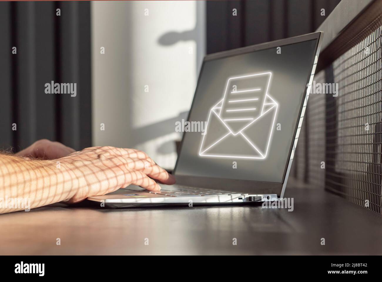 Spam-E-Mail. Mann, der Junk-E-Mails, unerwünschte Nachrichten und Werbung für Geldbetrug erhält, während er an einem Laptop arbeitet. Hände auf der Tastatur Nahaufnahme. Hochwertige Fotos Stockfoto
