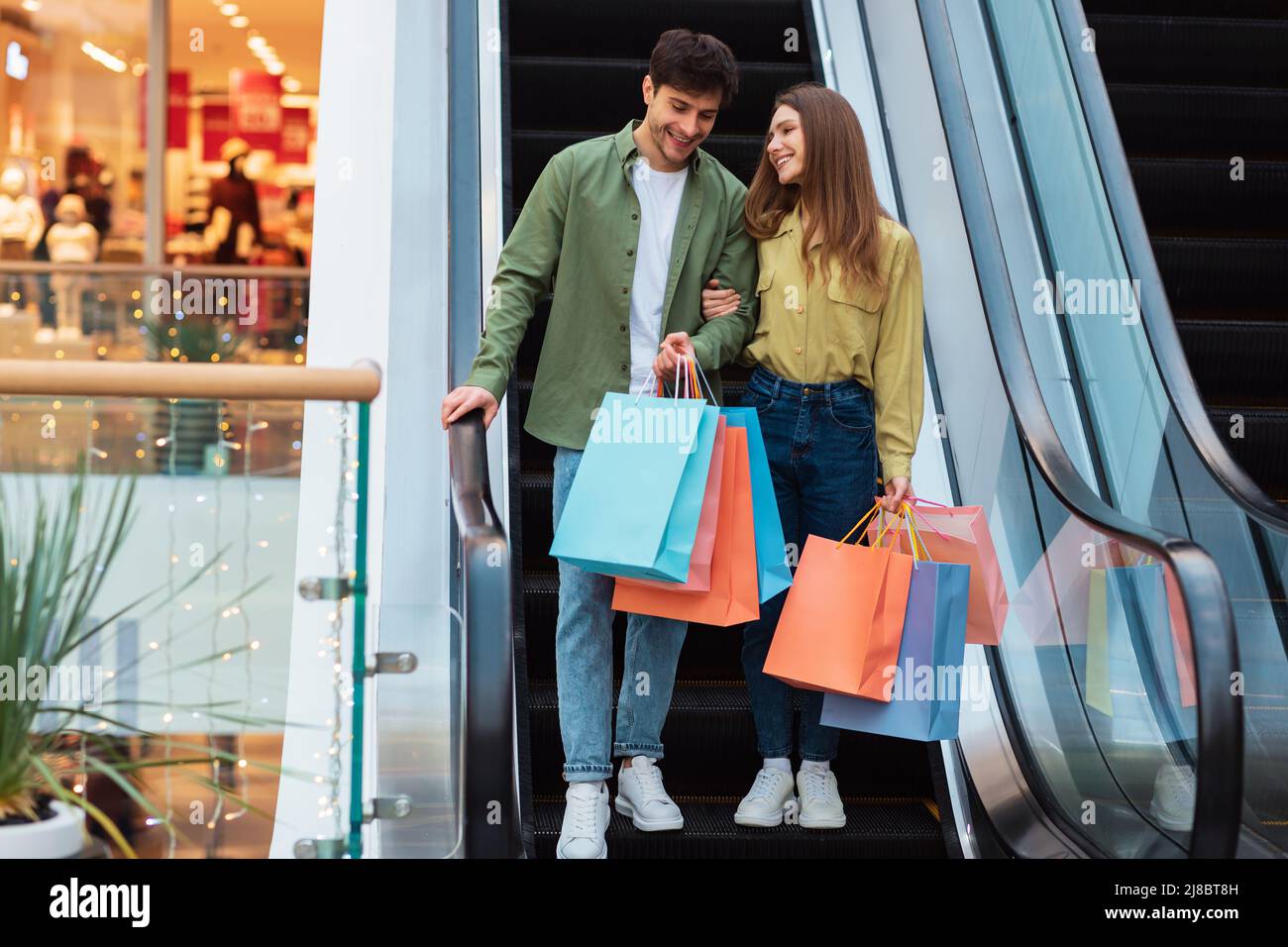 Ehepartner Beim Einkaufen Stehen Auf Treppen Mit Taschen In Der Mall Stockfoto