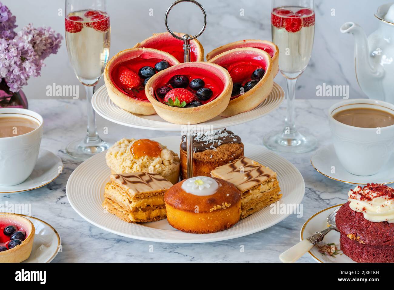 Auswahl an Gourmet-Kuchen mit Kaffee und Sekt auf einem Tisch Stockfotografie
