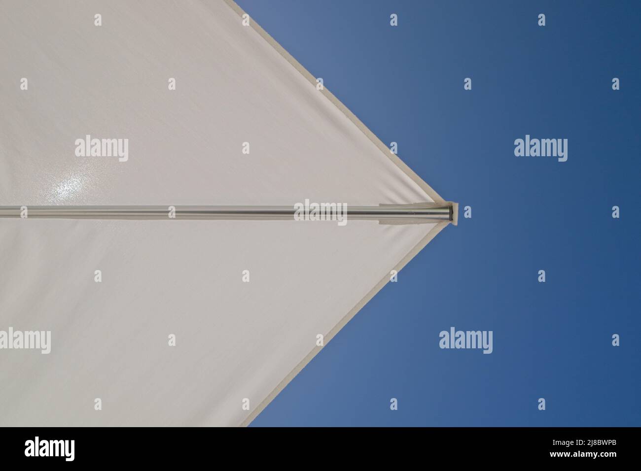 Die Ecke einer weißen Sonne brolley gesetzt gegen einen wolkenlosen blauen Himmel. Stockfoto