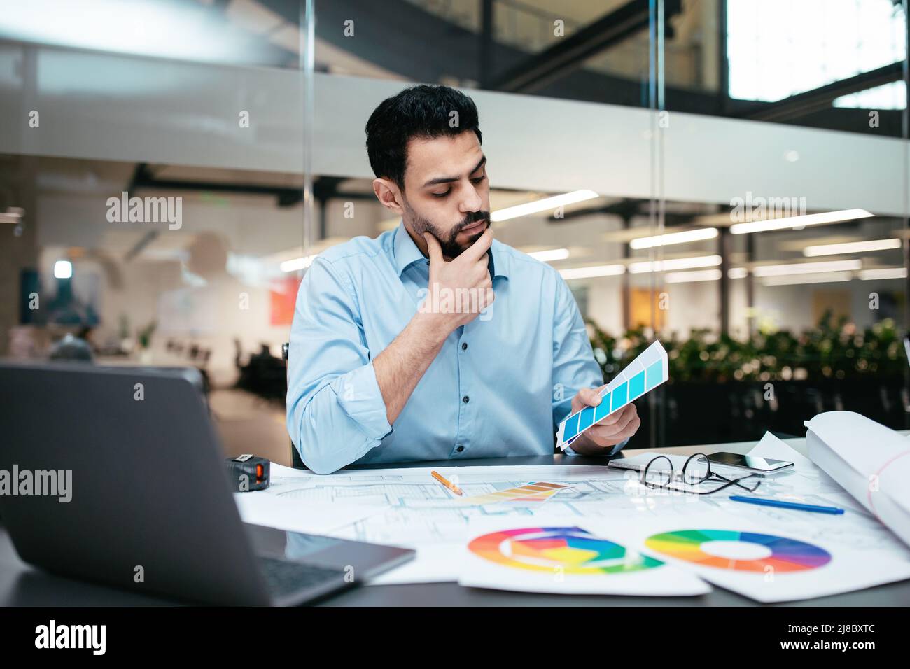 Serious smart gut aussehend Millennial islamischen Mann Designer mit Bart im Hemd wählt Ton auf Farbpalette Stockfoto