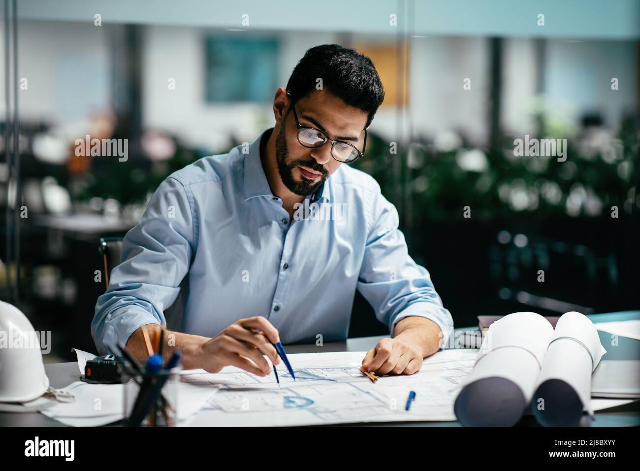 Konzentrierter, beschäftigter, gutaussehender, tausendjähriger islamischer Ingenieur mit Bart in einer Brille, denke an das Projekt Stockfoto