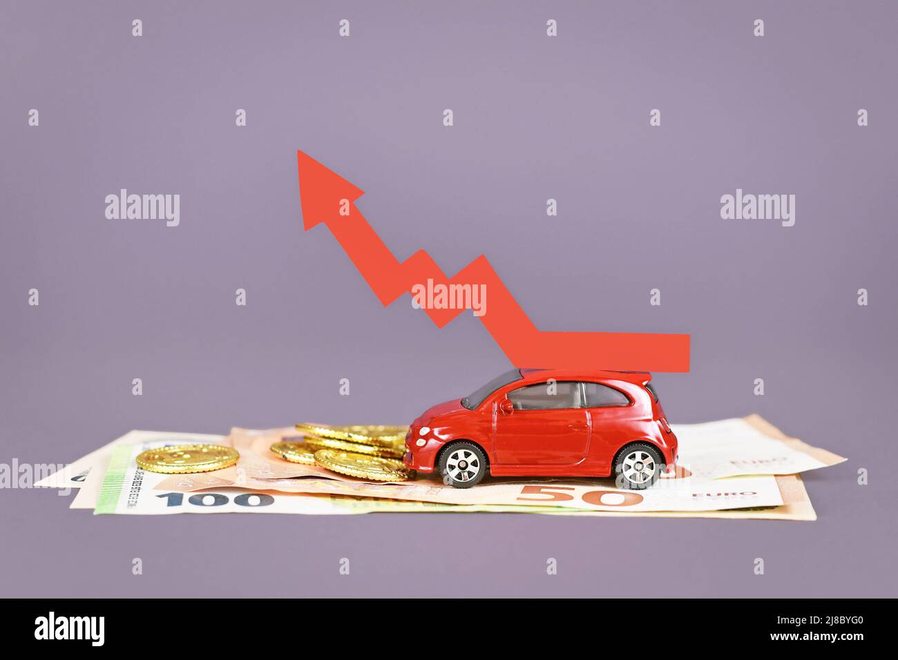 Rotes Auto mit aufsteigendem Pfeil und Geldmünzen und Scheinen Stockfoto