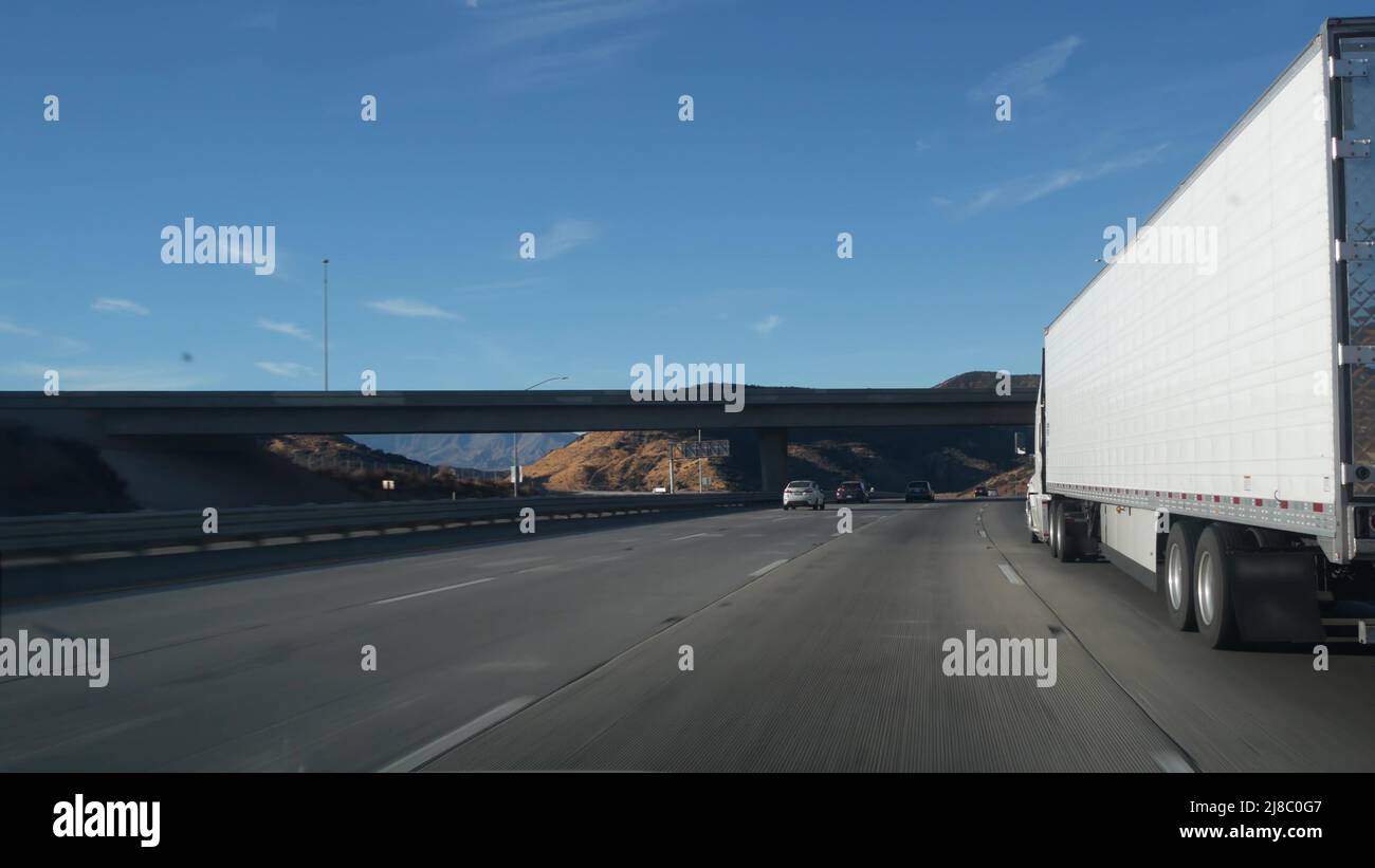 LKW oder Sattelauflieger auf der Autobahn, Gütertransport in Kalifornien, USA. Weißer Container, der auf der Autobahn transportiert oder transportiert wird. Kommerzielle Transportlogistik, Transporter. Autos fahren. Stockfoto