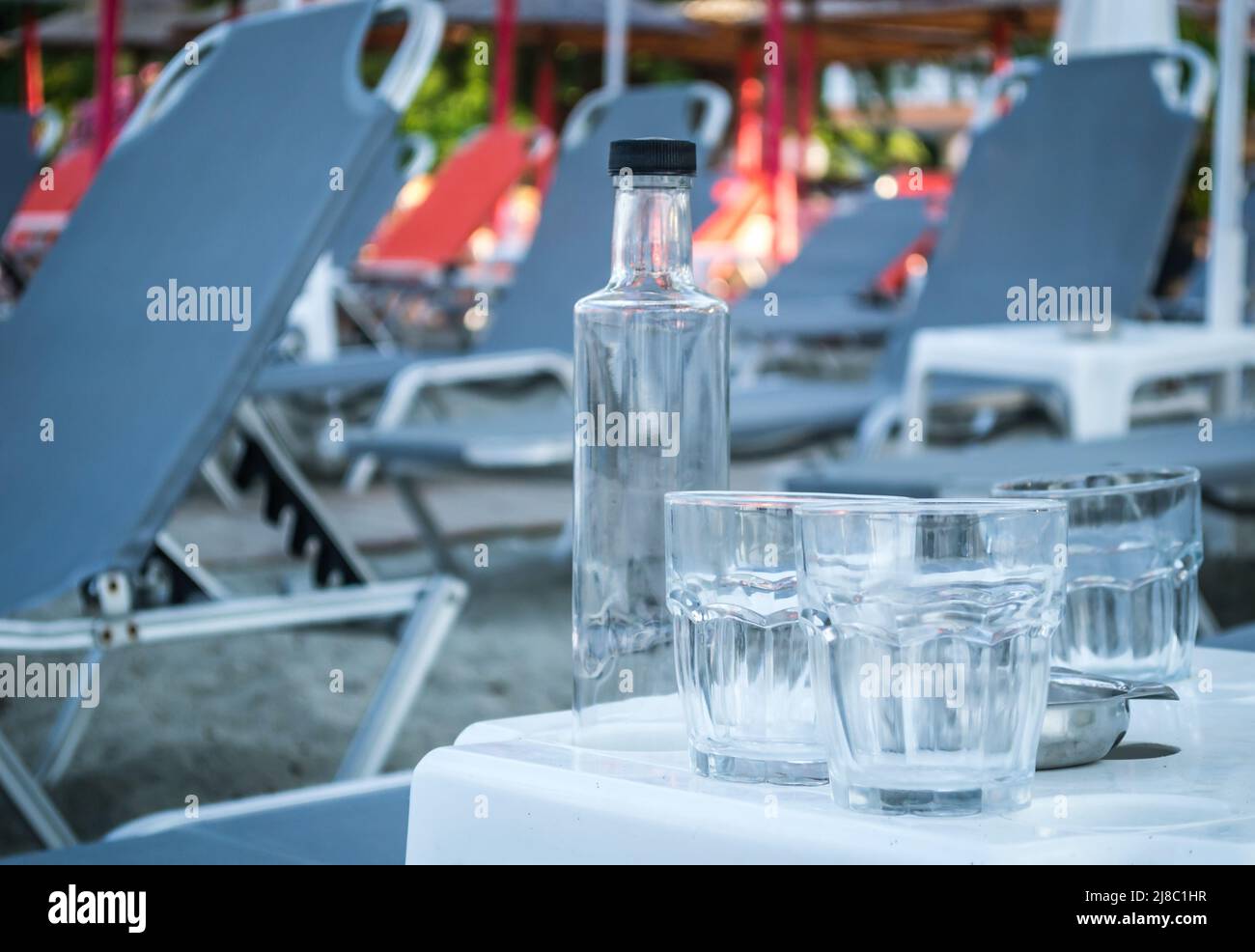 Ein kleiner ruhiger Touristenort Leptokarya in Griechenland. Leere Glaswasserflaschen und Trinkgläser auf einem Tisch in Griechenland. Stockfoto