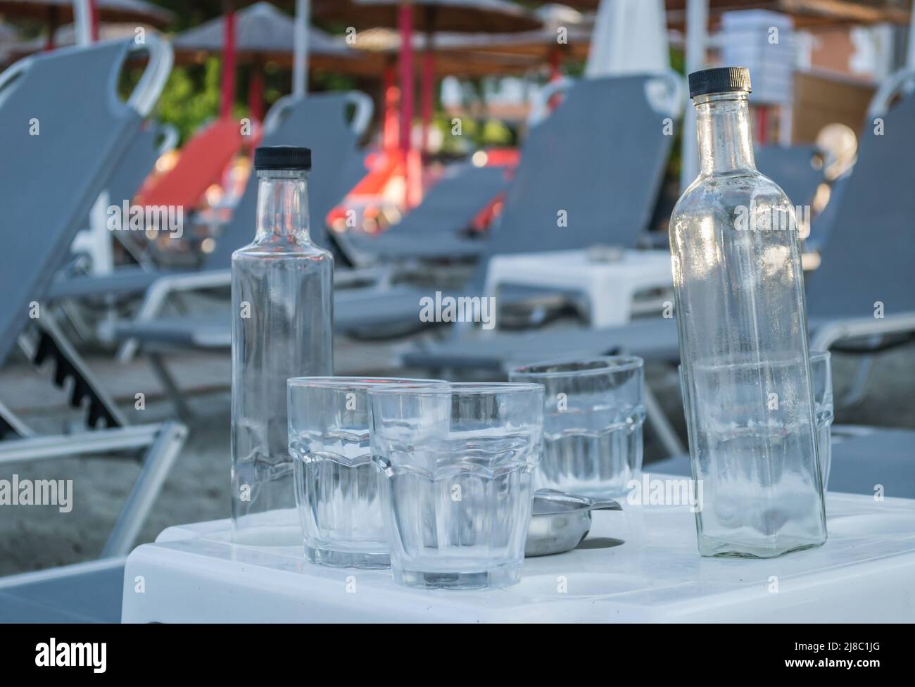 Ein kleiner ruhiger Touristenort Leptokarya in Griechenland. Leere Glaswasserflaschen und Trinkgläser auf einem Tisch in Griechenland. Stockfoto