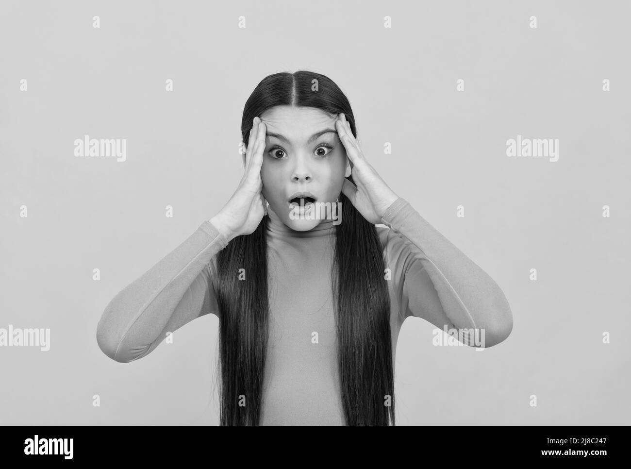 Schockiert Teenager-Mädchen mit langen Haaren auf gelbem Hintergrund, Emotionen Stockfoto