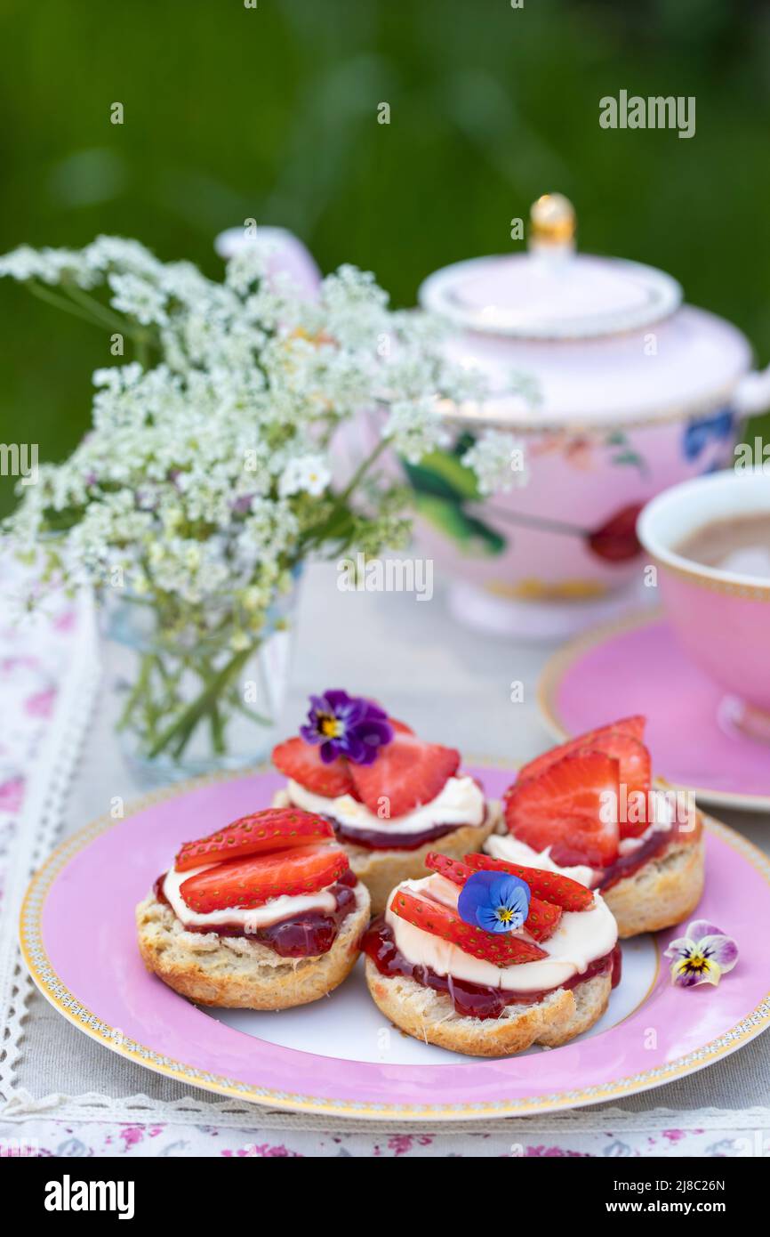 Frisch gebackene Scones mit Tee werden im Garten serviert Stockfoto