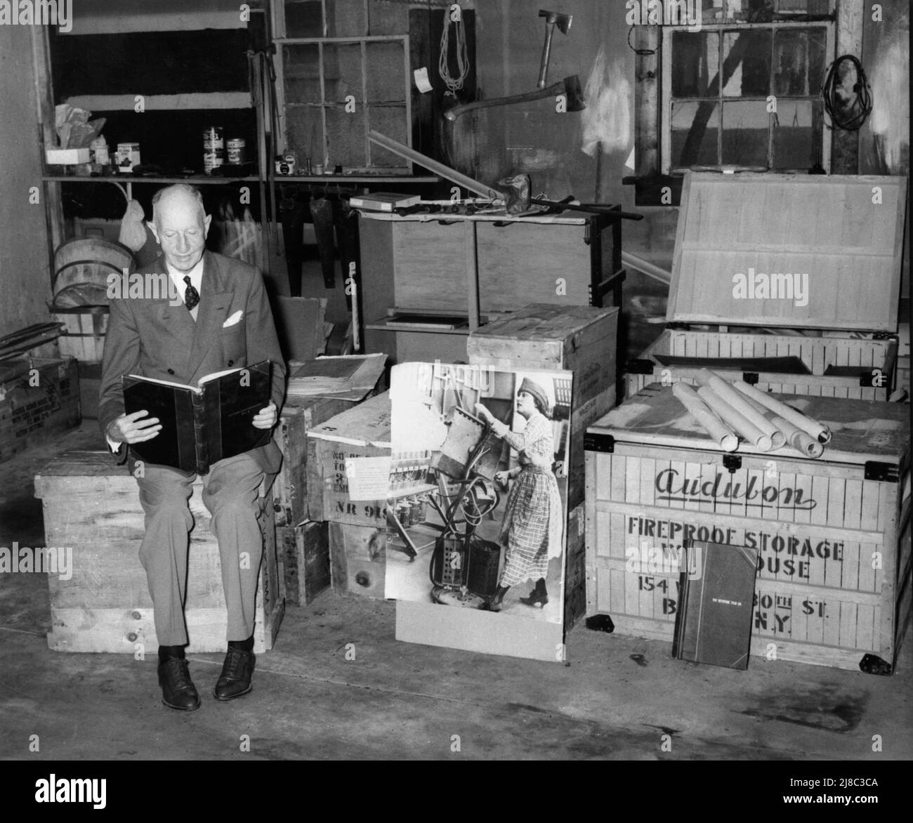 ROY AITKIN im Alter von 74 Jahren Anfang 1957 in einem Lagerhaus, das ein Sammelalbum aus einem der 17 Kisten mit Aufzeichnungen des Pionierfilmstudios TRIANGLE FILM CORPORATION ansah, das im Juli 1915 von Roy Aitkin und seinem Bruder Harry Aitkin in Culver City gegründet wurde, Kalifornien und überleben bis 1922. Stockfoto