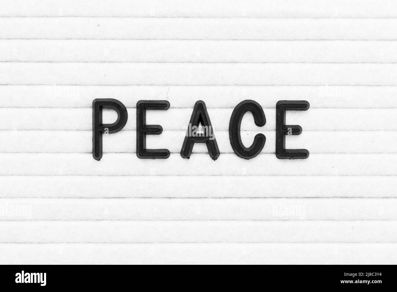 Schwarzer Buchstabe in Wort Frieden auf weißem Filzbrett Hintergrund Stockfoto