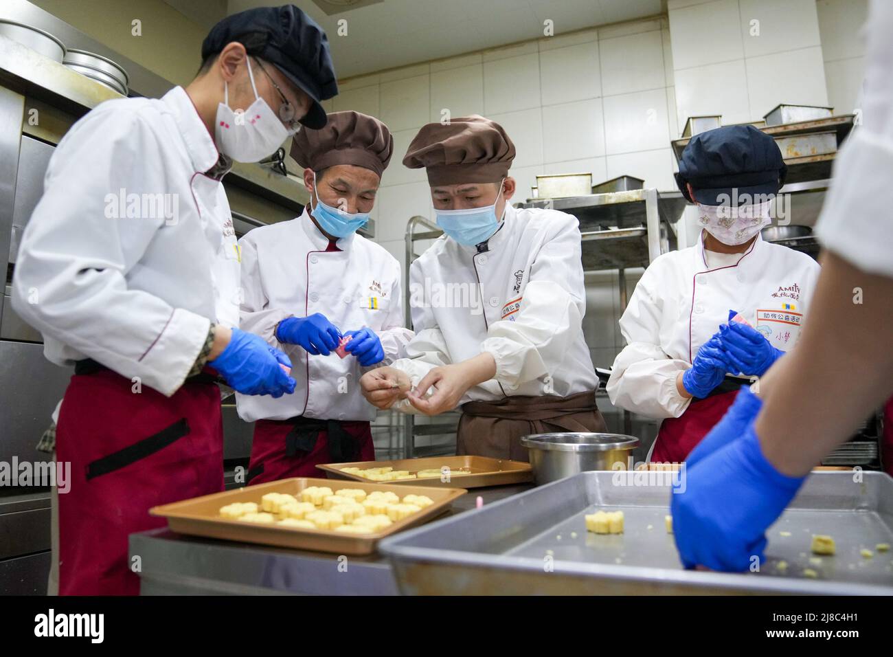 (220515) -- NANJING, 15. Mai 2022 (Xinhua) -- geistig behinderte Mitarbeiter bereiten in der Bäckerei Amity in Nanjing, der ostchinesischen Provinz Jiangsu, grüne Bohnenkuchen zu, 10. Mai 2022. Die Bäckerei wurde 2007 gegründet und bietet in den letzten 15 Jahren fast 100 geistig behinderten Menschen berufliche Ausbildungs- und Beschäftigungsmöglichkeiten. (Xinhua/Li Bo) Stockfoto
